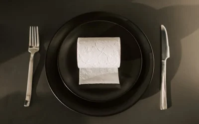 Creative still life setup of a dinner plate with a toilet paper roll, fork, and knife.