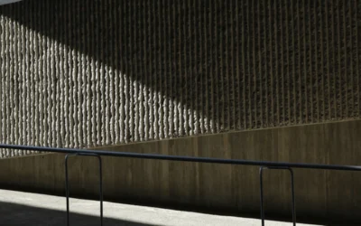 a man riding a skateboard down a sidewalk next to a wall