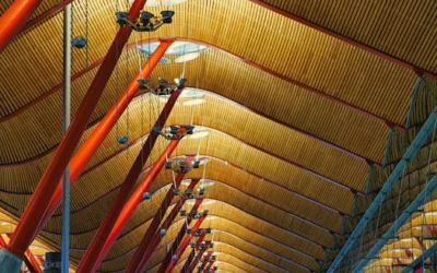 Intricate ceiling design of Madrid Barajas Airport with red poles and geometric patterns.