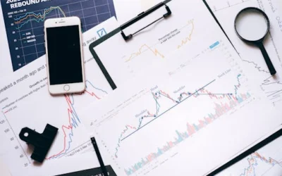 Stock market analysis setup with charts, phone, magnifier, and clipboards.
