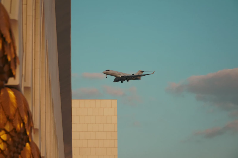 A large jetliner flying over a tall building