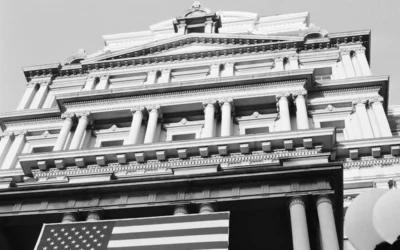 A large, classical building displays the american flag.