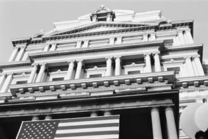 A large, classical building displays the american flag.