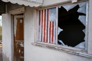 An old building with a broken window and american flag on it