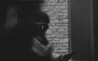 grayscale photography of person's profile standing beside gray wall