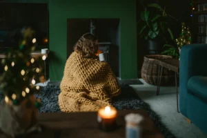 a woman wrapped in a blanket sitting on a rug in a living room