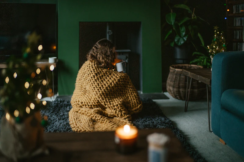 a woman wrapped in a blanket sitting on a rug in a living room