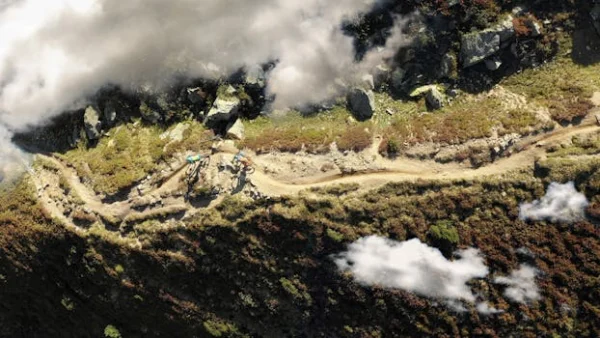 Drone shot of cyclists biking on a scenic mountain trail in Davos, Switzerland.