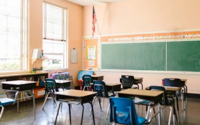 An inviting, sunlit classroom with empty desks and an American flag, ready for students.