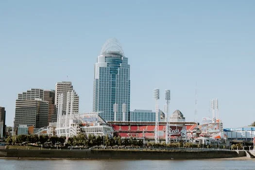Photo of Cincinnati skyline with Great American Ball Park and modern skyscrapers, captured from a riverside view.