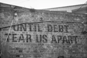 a sign on a brick wall that says until debt tears apart