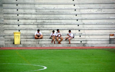 four boys wearing white shirt sitting near field