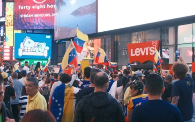 A crowd of people walking down a street next to tall buildings