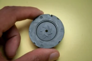 Detailed view of a camera lens component held by a human hand, showcasing precision.