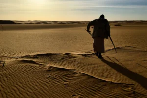 man in black shirt and black pants standing on brown sand during daytime