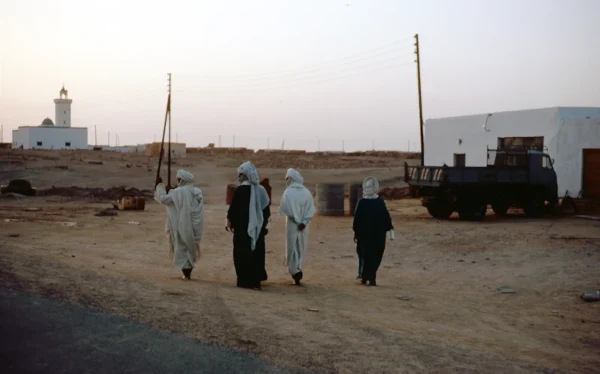 a group of people walking down a dirt road