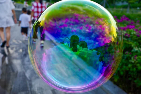 A soap bubble floating in the air over a sidewalk