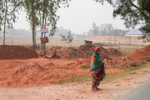Woman standing near piles of dirt and bricks.