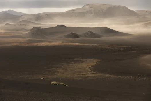 Captivating mist over vast desert landscape with rolling hills and distant mountains.