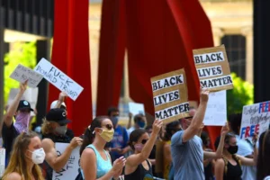 Protesters gather with signs supporting Black Lives Matter and denouncing Donald Trump in a peaceful rally.