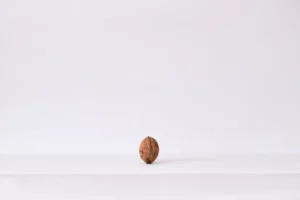 A single walnut placed on a clean white surface offering versatile copyspace for text overlay.