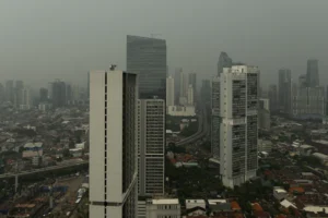 Modern skyscrapers rise above a dense cityscape under hazy skies.