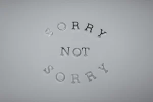Minimalist design featuring the phrase 'Sorry Not Sorry' arranged in a circular pattern on a white background.