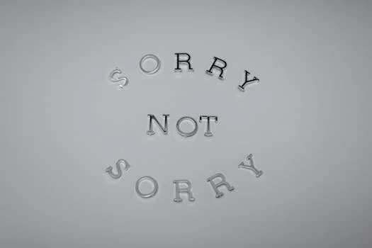 Minimalist design featuring the phrase 'Sorry Not Sorry' arranged in a circular pattern on a white background.