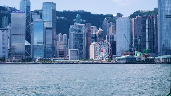 Stunning view of Hong Kong skyline with skyscrapers and observation wheel from Victoria Harbour.