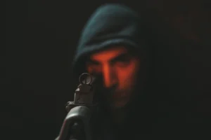 man in black hoodie holding black rifle