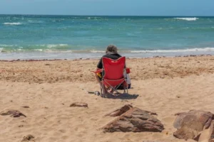 An adult sitting and relaxing by the ocean in Jeffreys Bay, capturing summer tranquility.