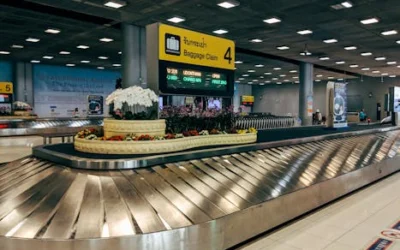 Modern baggage claim area at Suvarnabhumi Airport in Bangkok with luggage carousel and signage.
