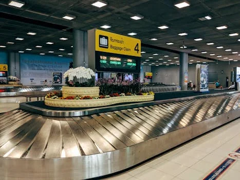 Modern baggage claim area at Suvarnabhumi Airport in Bangkok with luggage carousel and signage.