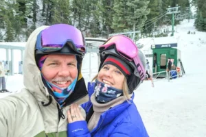 A happy couple in ski gear poses at Sundance Resort ski lift, Utah.