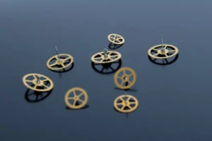 Close-up of golden gears scattered on a reflective dark surface.