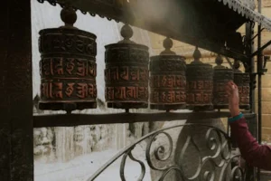A close-up of prayer wheels being spun by a hand, depicting spirituality and Buddhism.