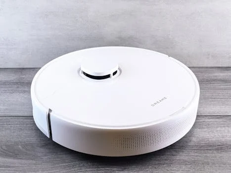 Sleek white robot vacuum cleaner on a wooden floor, perfect for smart home setups.