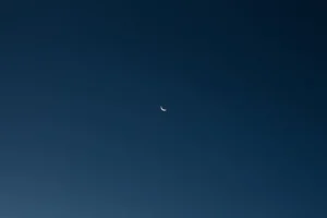 Crescent moon against a dark blue, minimalist night sky. Captivating celestial view.