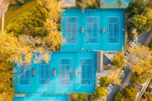 A vibrant aerial view showcasing multiple tennis courts surrounded by autumn trees.