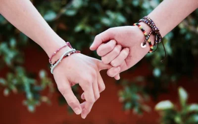 Two hands with colorful bracelets interlocked, symbolizing friendship and connection.