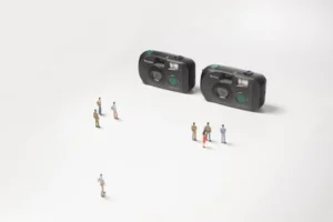 Creative scene with tiny people and classic cameras on a white surface, highlighting photography nostalgia.