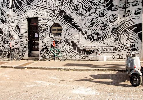 A vibrant black-and-white mural featuring bicycles and a scooter on an urban street.