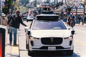 A self-driving car navigates through a bustling city street in San Francisco, capturing urban mobility in action.
