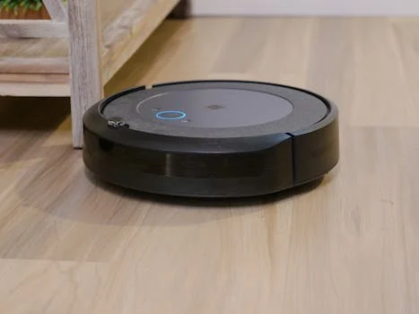 Autonomous vacuum cleaner navigating wooden floor indoors, showcasing smart home technology.