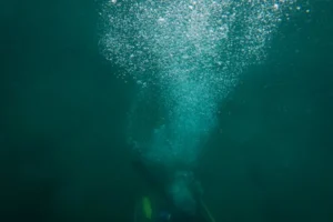 A scuba diver creates a trail of bubbles while exploring the deep ocean underwater.