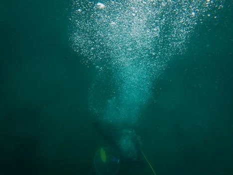 A scuba diver creates a trail of bubbles while exploring the deep ocean underwater.