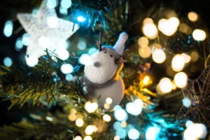 Close-up of a reindeer ornament on a Christmas tree with festive bokeh lights, capturing holiday spirit.