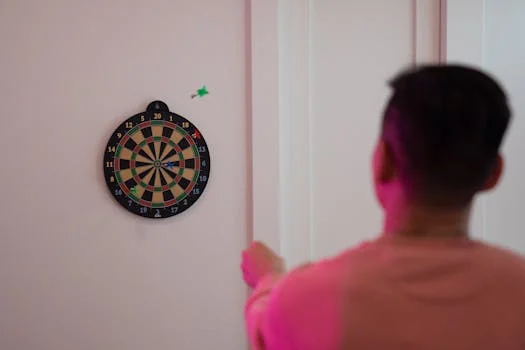 A person aims at a dartboard on a wall, showcasing precision and focus.
