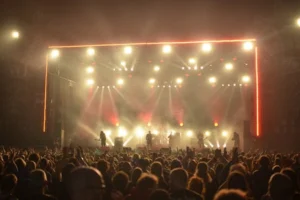 Dynamic live concert with band on stage, lighting effects, and enthusiastic crowd at night.