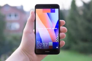 Hand holding a Huawei smartphone displaying a colorful screen outdoors in Germany.